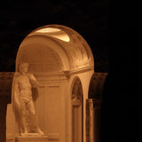 Statue of a man in a classical architectural setting with a dark background
