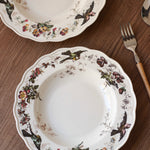 Decorative ceramic plates with floral and bird patterns on a wooden surface.
