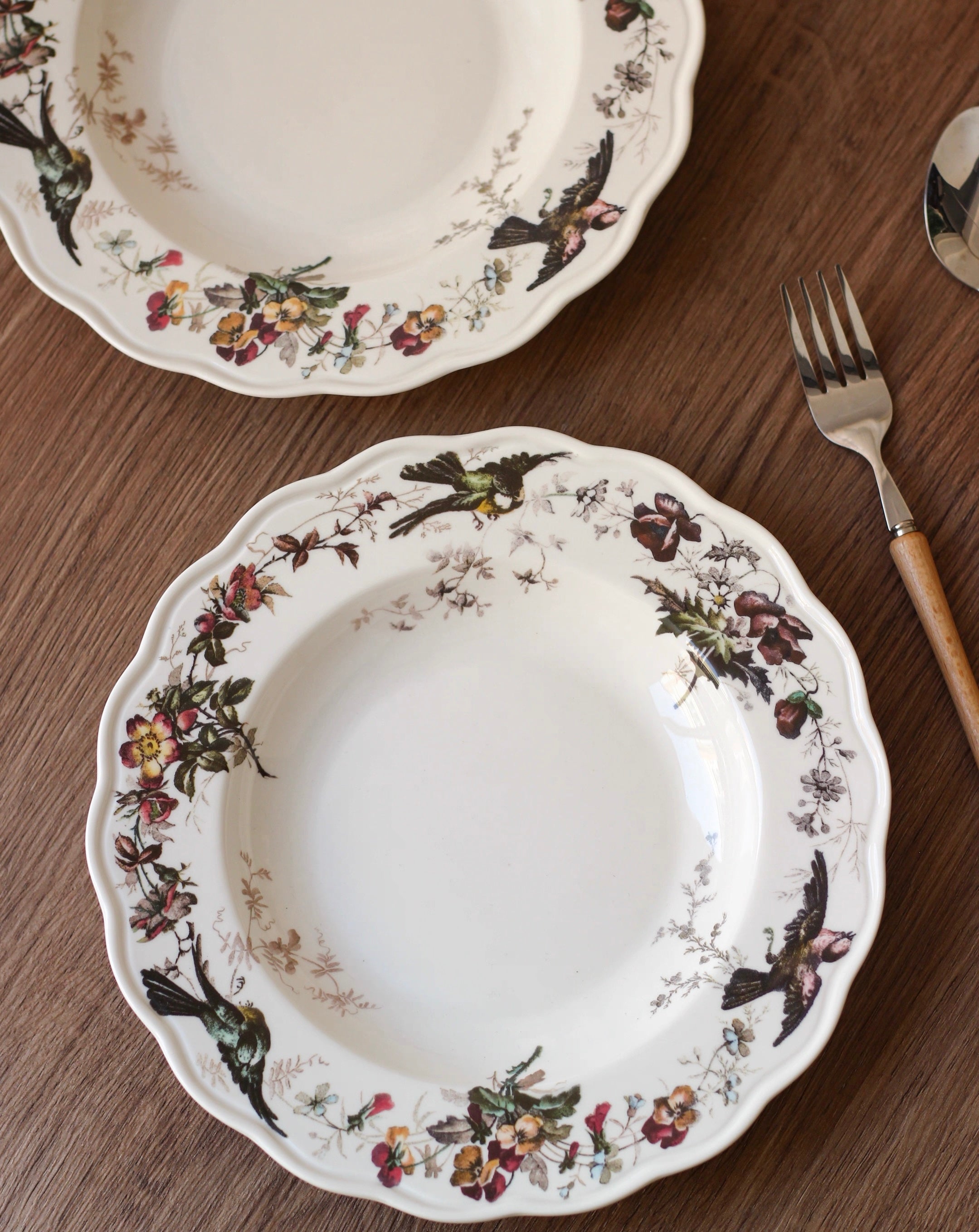 Decorative ceramic plates with floral and bird patterns on a wooden surface.