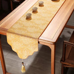 Yellow table runner with tassel on a wooden table