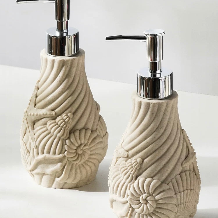 Two decorative soap dispensers with shell designs on a white background