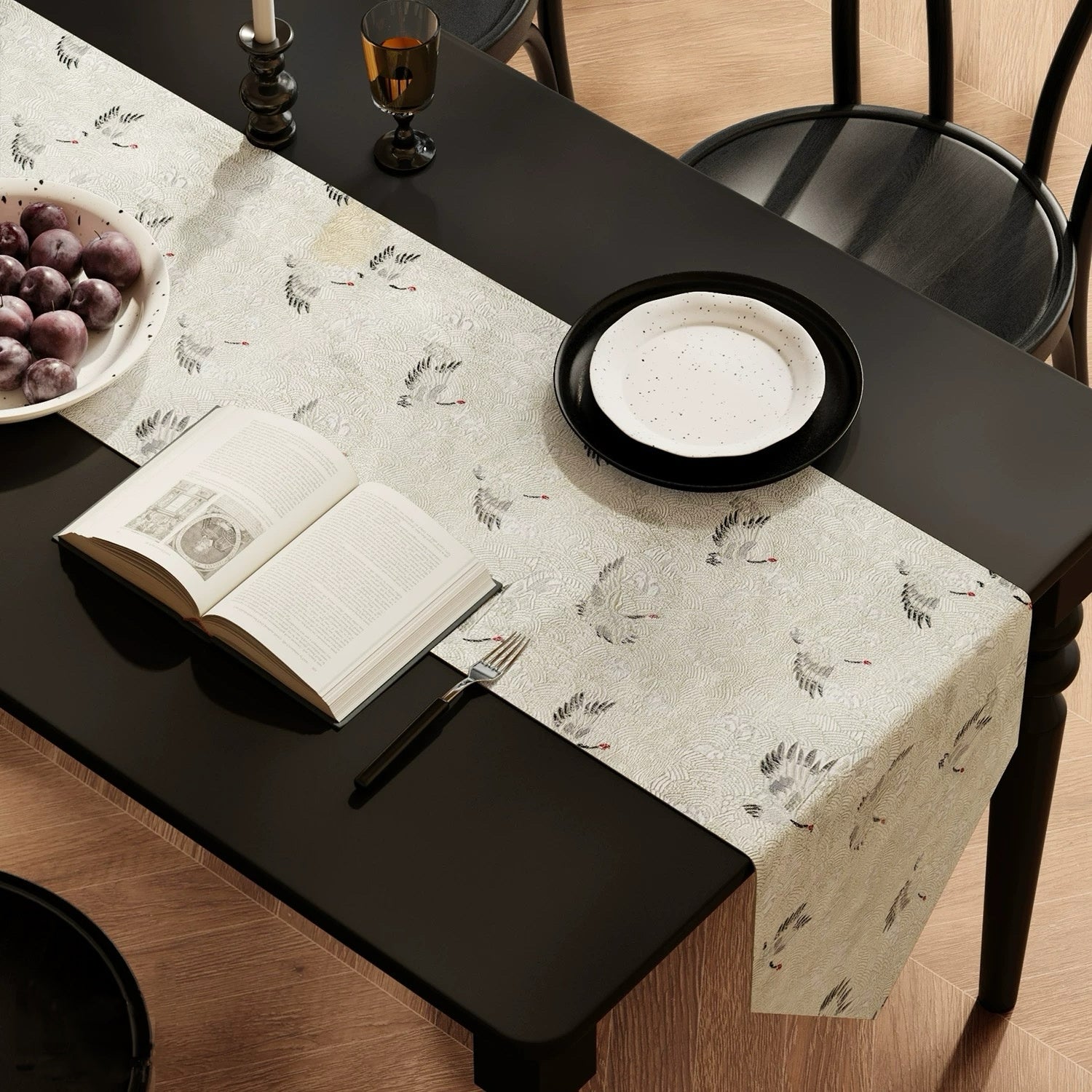 Table setting with a patterned table runner, open book, and fruit on a black table.