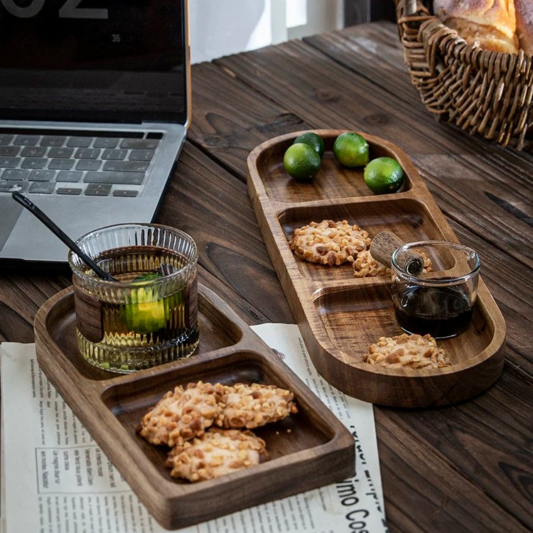 Wooden trays with snacks and drinks on a wooden table with a laptop and newspaper.