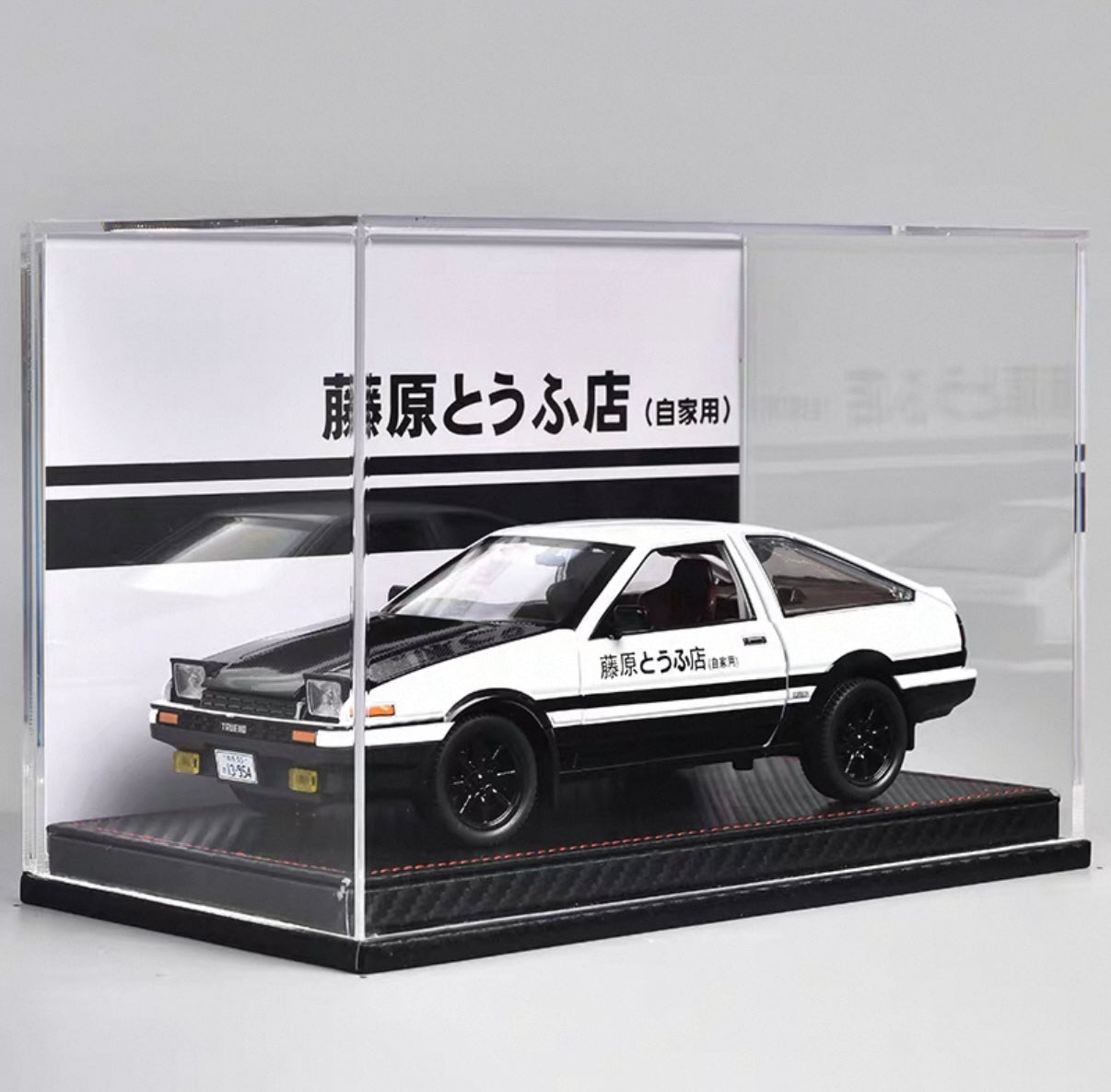 Model car in a clear display case with Japanese text on the background