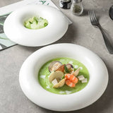 Two bowls of green soup with seafood on a gray surface.