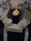 Candle in a decorative box with floral design on a dark background