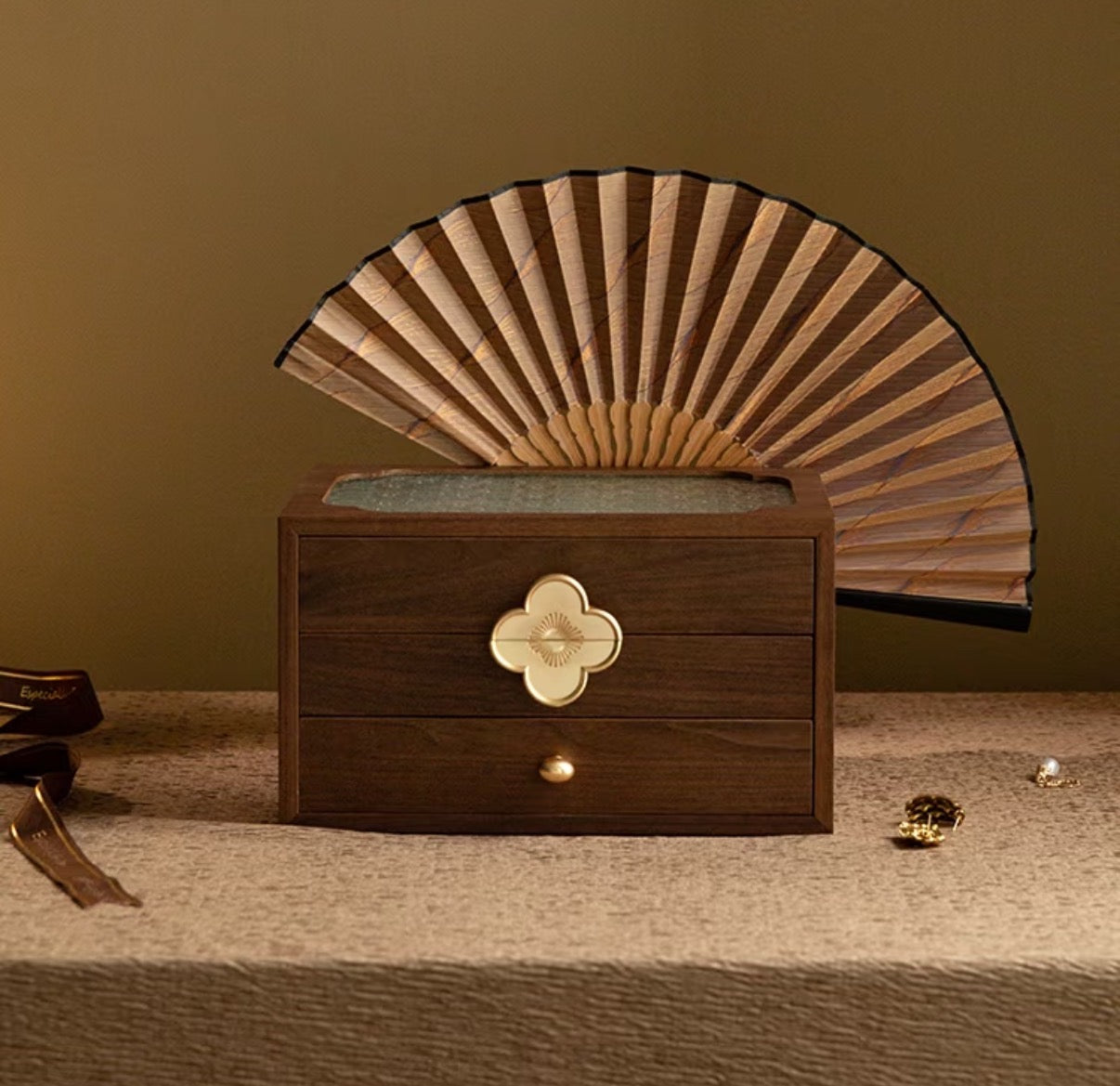 Wooden jewelry box with a decorative fan on top against a brown background