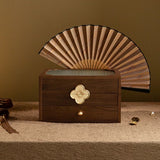 Wooden jewelry box with a decorative fan on top against a brown background