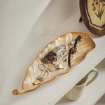 Decorative leaf-shaped tray with jewelry on a shelf