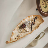 Decorative leaf-shaped tray with jewelry on a shelf