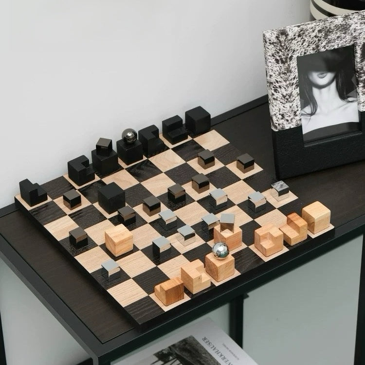 Wooden chessboard with black and light wood pieces on a table.