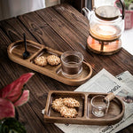 Wooden trays with cookies and a glass, teapot on a wooden table.
