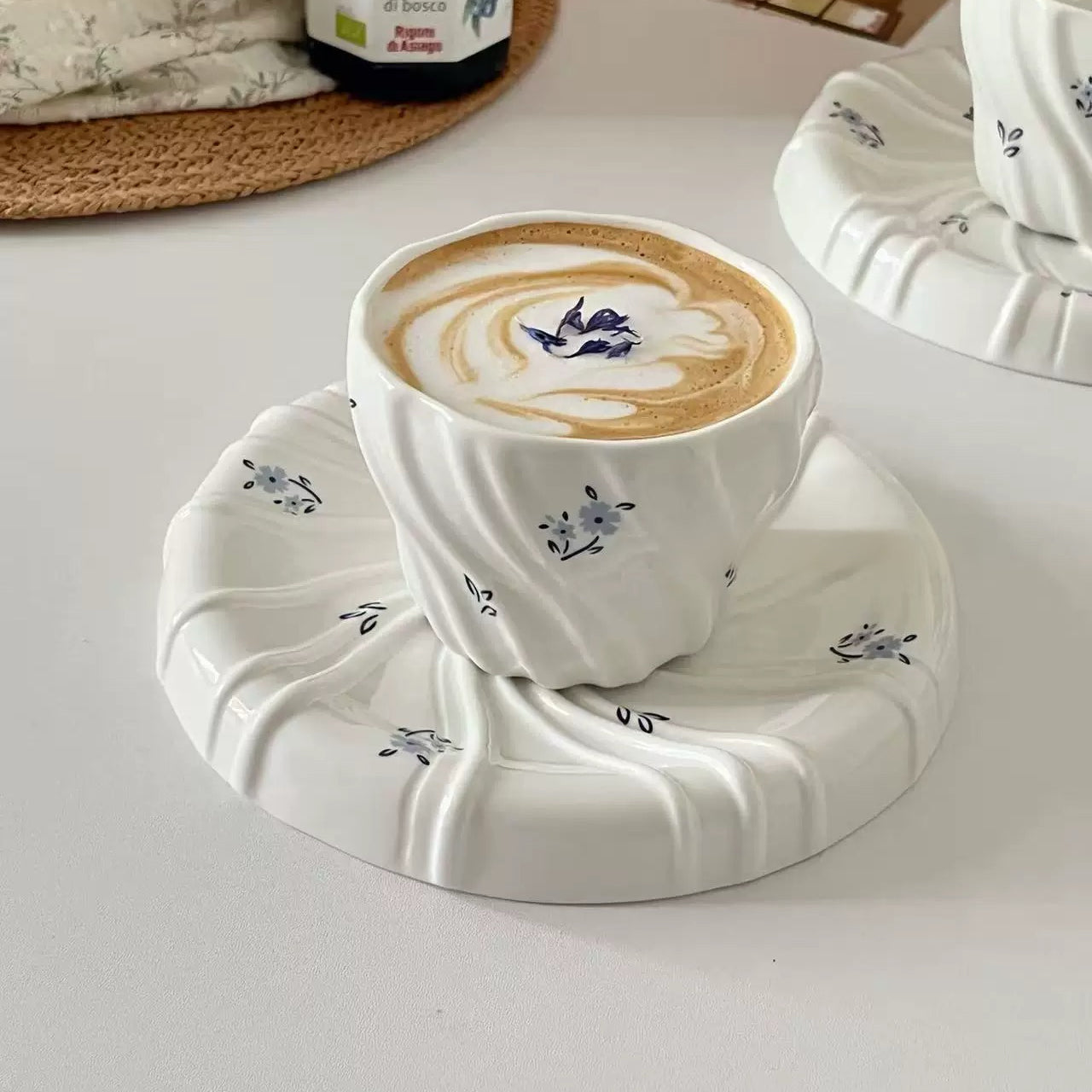 Cup of coffee with latte art on a decorative coaster on a light surface.