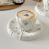 Cup of coffee with latte art on a decorative coaster on a light surface.