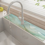 Modern kitchen sink with a white faucet and greenish countertop.