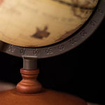 Close-up of a vintage-style globe with a wooden base on a dark background