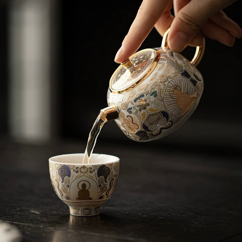 Tea being poured from an ornate teapot into a matching cup on a dark surface.