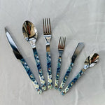 Set of silver cutlery with floral handles on a white background