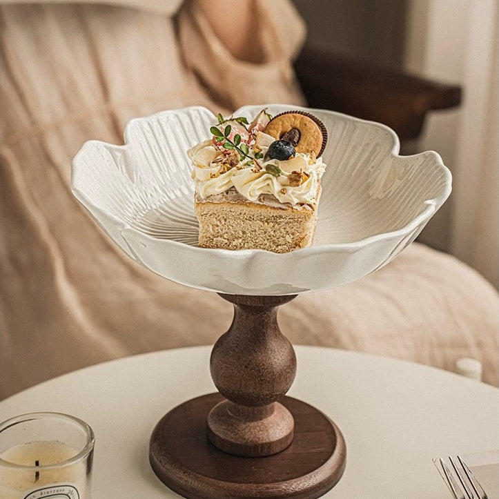 Small cake on a decorative stand with a candle and menu in the background