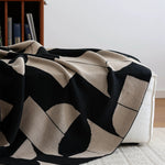 Black and beige patterned throw blanket on a sofa in a living room setting.