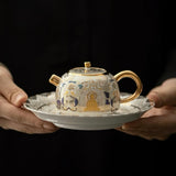 Ceramic teapot with intricate designs held by two hands on a dark background