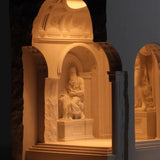Stone sculpture of a seated figure in an archway with warm lighting