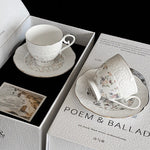 White ceramic cup and saucer set on a box labeled 'POEM & BALLAD' with a black background.
