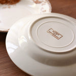 White ceramic plate with a brand logo on a wooden surface