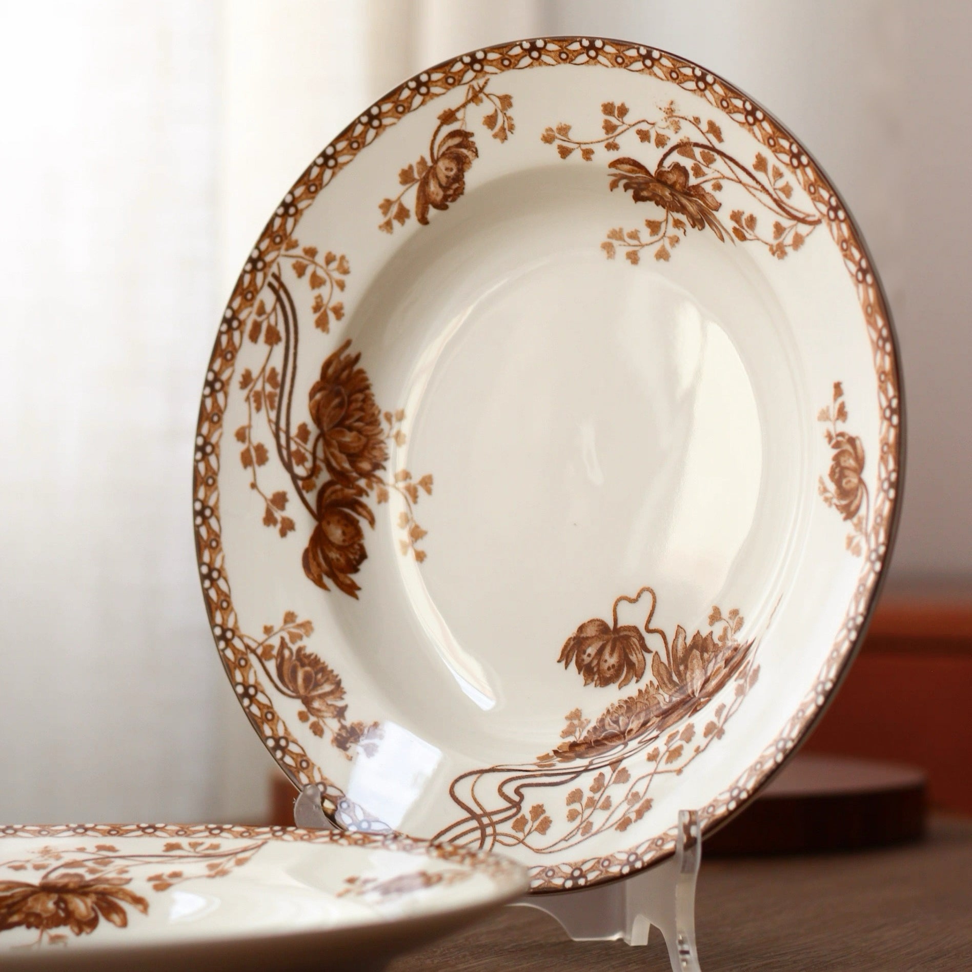 White plate with brown floral patterns on a stand