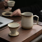 Ceramic pitcher and cup on a wooden surface with blurred background