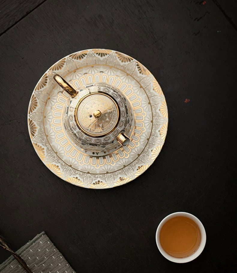 Decorative teapot on a black surface with a cup of tea nearby
