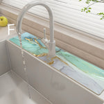 Modern kitchen sink with marble-like green  countertop and white faucet.