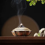 Decorative incense burner with smoke on a wooden surface
