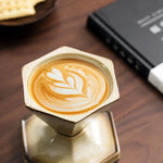 Hexagonal metal stand with a cappuccino on a wooden surface