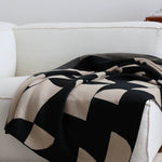 Black and beige patterned blanket draped over a white sofa.