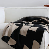 Black and beige patterned blanket draped over a white sofa.