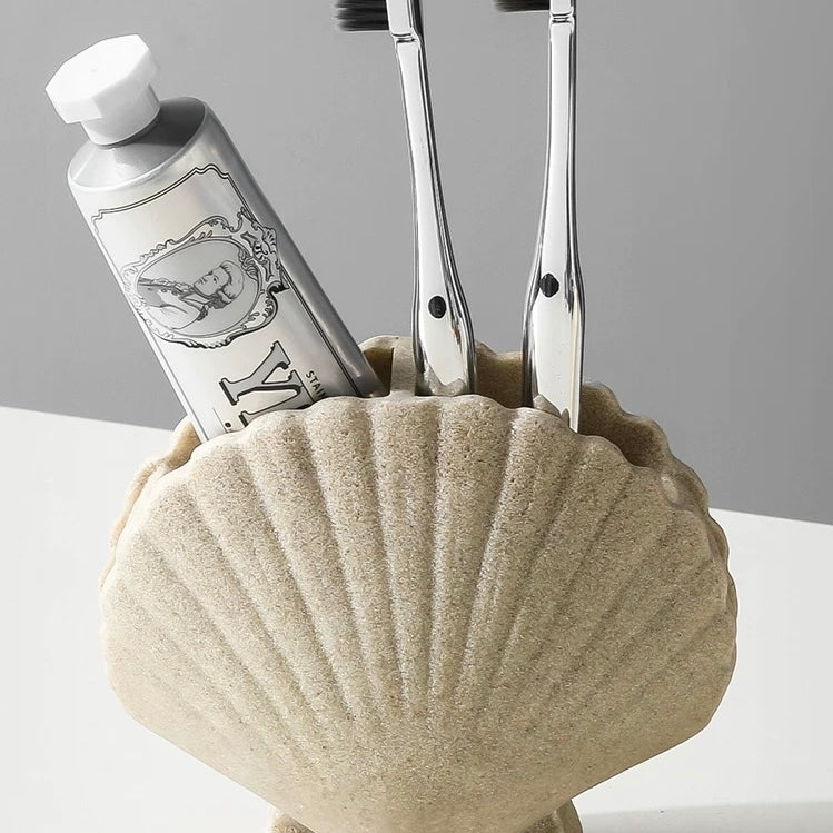 Shell-shaped holder with toothbrushes and toothpaste on a gray background