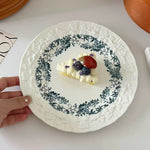 Decorative plate with a small dessert topped with berries on a white surface.
