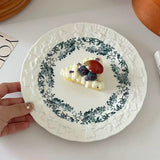 Decorative plate with a small dessert topped with berries on a white surface.