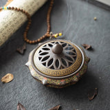 Decorative incense burner with intricate design on a dark surface