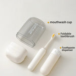 Set of travel dental hygiene products including a mouthwash cup, foldable toothbrush, and toothpaste dispenser on a white background.