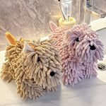 Two plush dog-shaped cleaning sponges, one beige and one pink, on a bathroom counter.