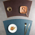 Two placemats, one brown and one blue, with a plate of food and cutlery on a gray surface.