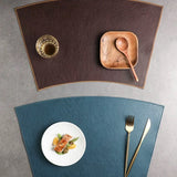 Two placemats, one brown and one blue, with a plate of food and cutlery on a gray surface.
