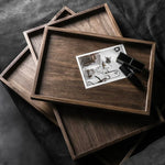 Stack of wooden trays with a black and white photo on top, on a dark fabric background