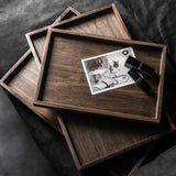 Stack of wooden trays with a black and white photo on top, on a dark fabric background