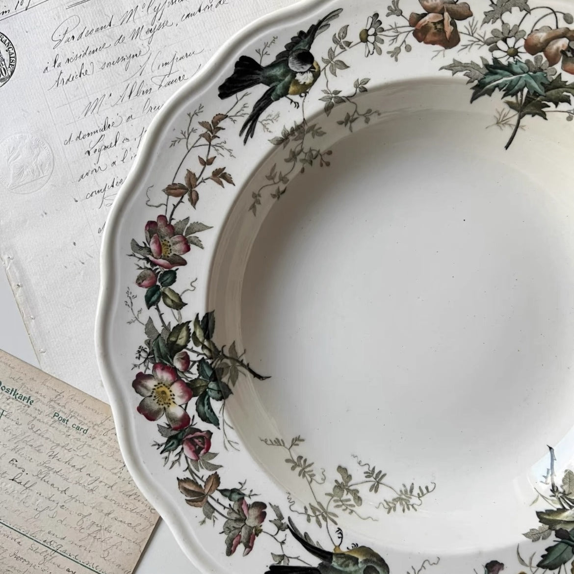 Decorative plate with floral and bird patterns on a surface with handwritten text.