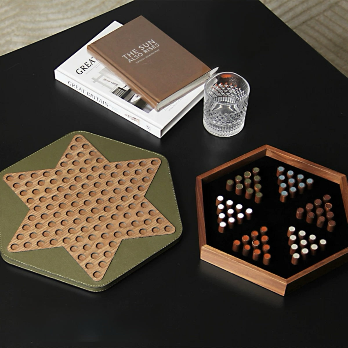Star-shaped wooden coaster on a green mat with a hexagonal wooden game board and dice on a dark surface.