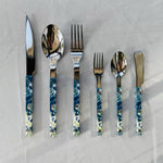 Set of silver cutlery with blue and white patterned handles on a light gray background