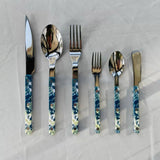 Set of silver cutlery with blue and white patterned handles on a light gray background
